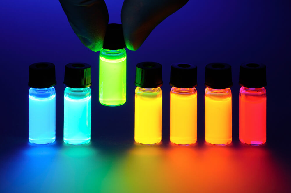 A row of small bottles that are different colors and are glowing .