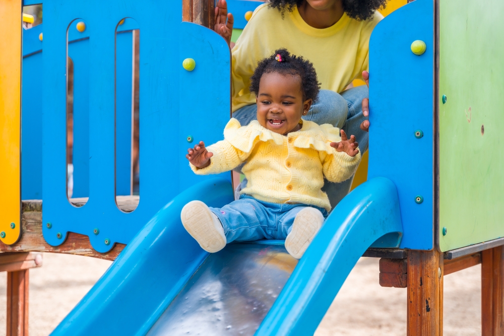 Child playing safely on a playground slide